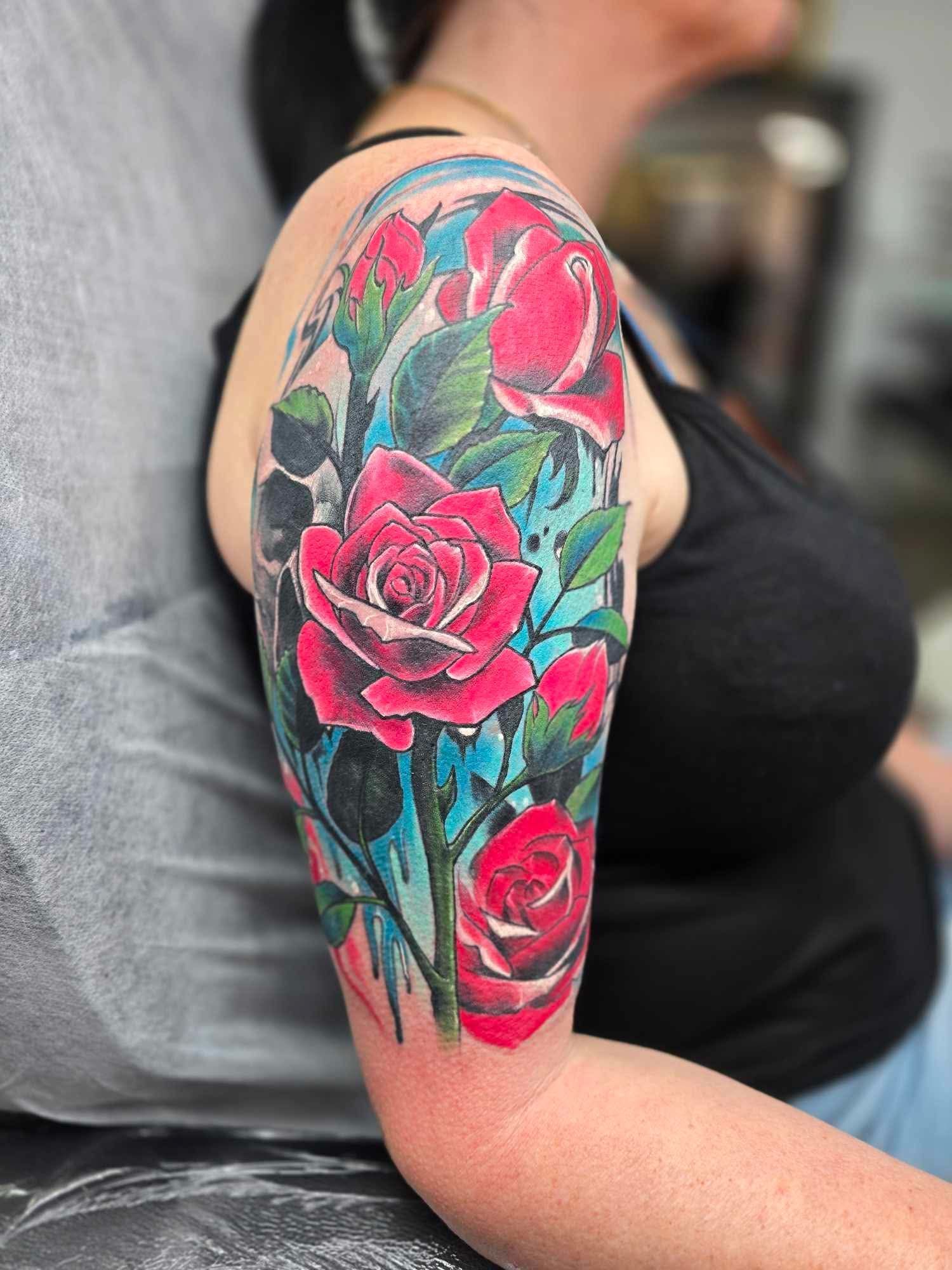 Rose Tattoo on Upper Arm, Featuring Red Roses, Blue and Green Accents — Redback !nk Tattoo Studio in Kawana, QLD