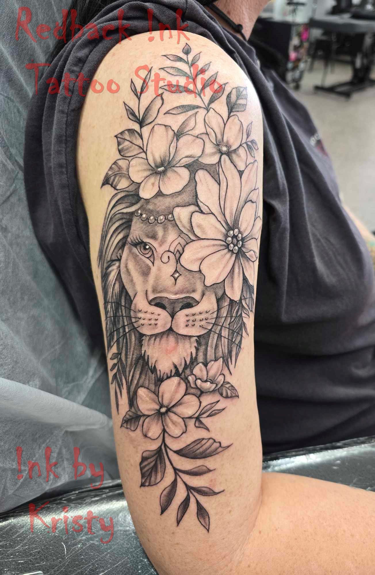 Lion face tattoo with floral crown on arm, shaded black and white. — Redback !nk Tattoo Studio in Kawana, QLD