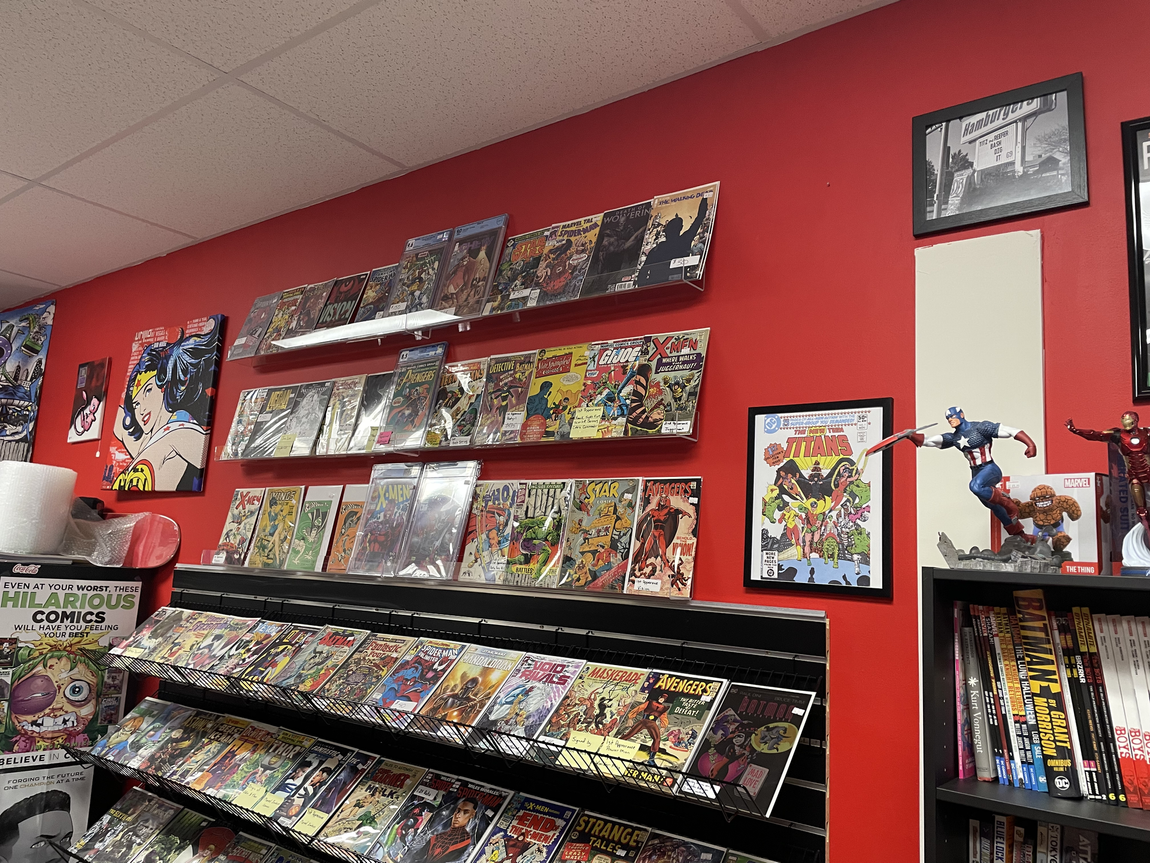 Comic books displayed on red walls and shelves in a store.
