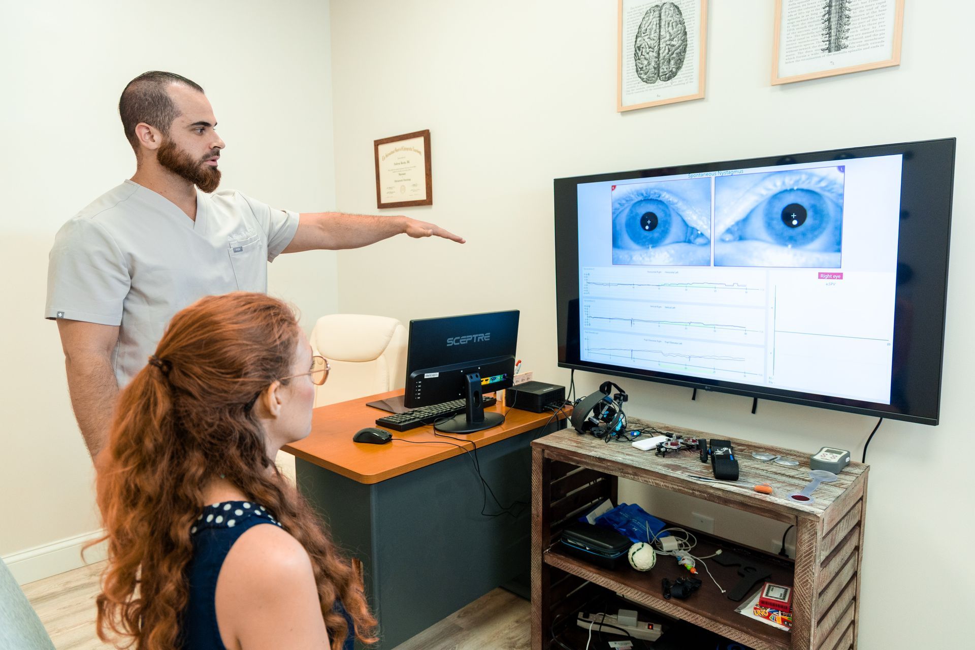 Two people reviewing an eye exam on a large monitor in a clinic office