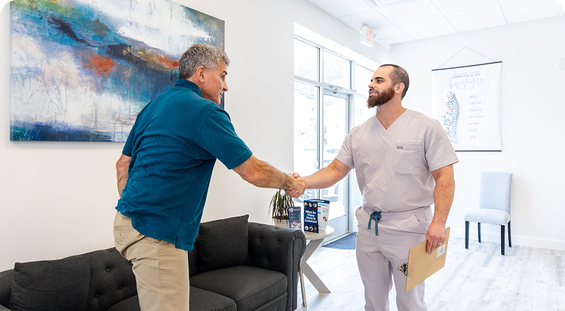 Man shaking hands with healthcare provider in a clinic. They are standing near a waiting area.