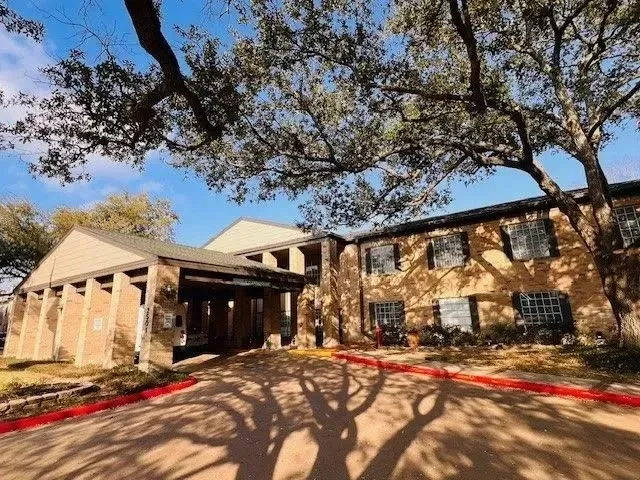 Building entrance with large trees at Treemont Senior Community in Houston, Texas