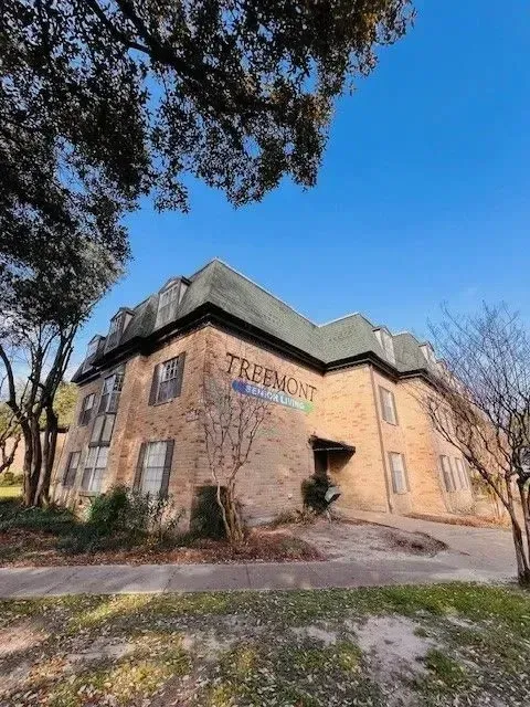 Brick building with trees and blue sky at Treemont Senior Community in Houston, Texas