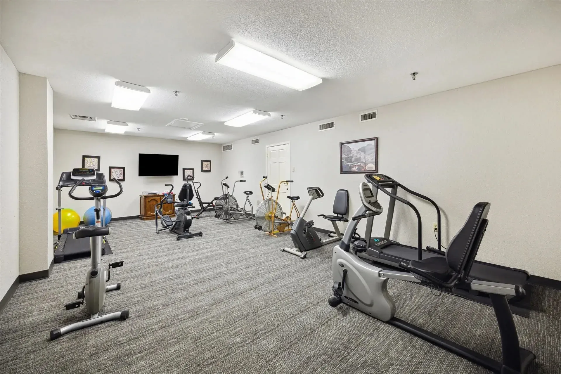 Exercise equipment in a carpeted room at Treemont Senior Community in Houston, Texas