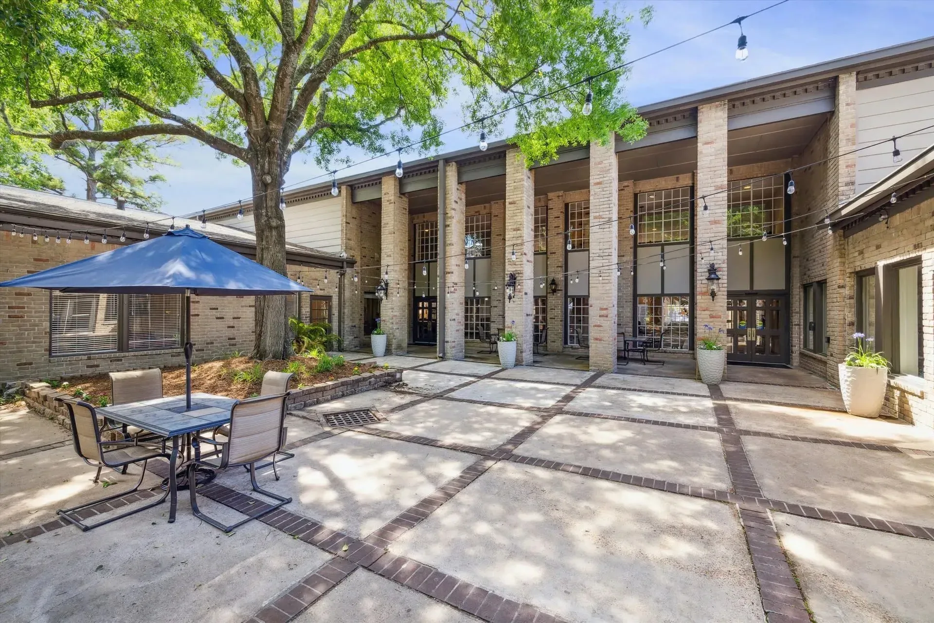 Table and chairs under blue umbrella at Treemont Senior Community in Houston, Texas