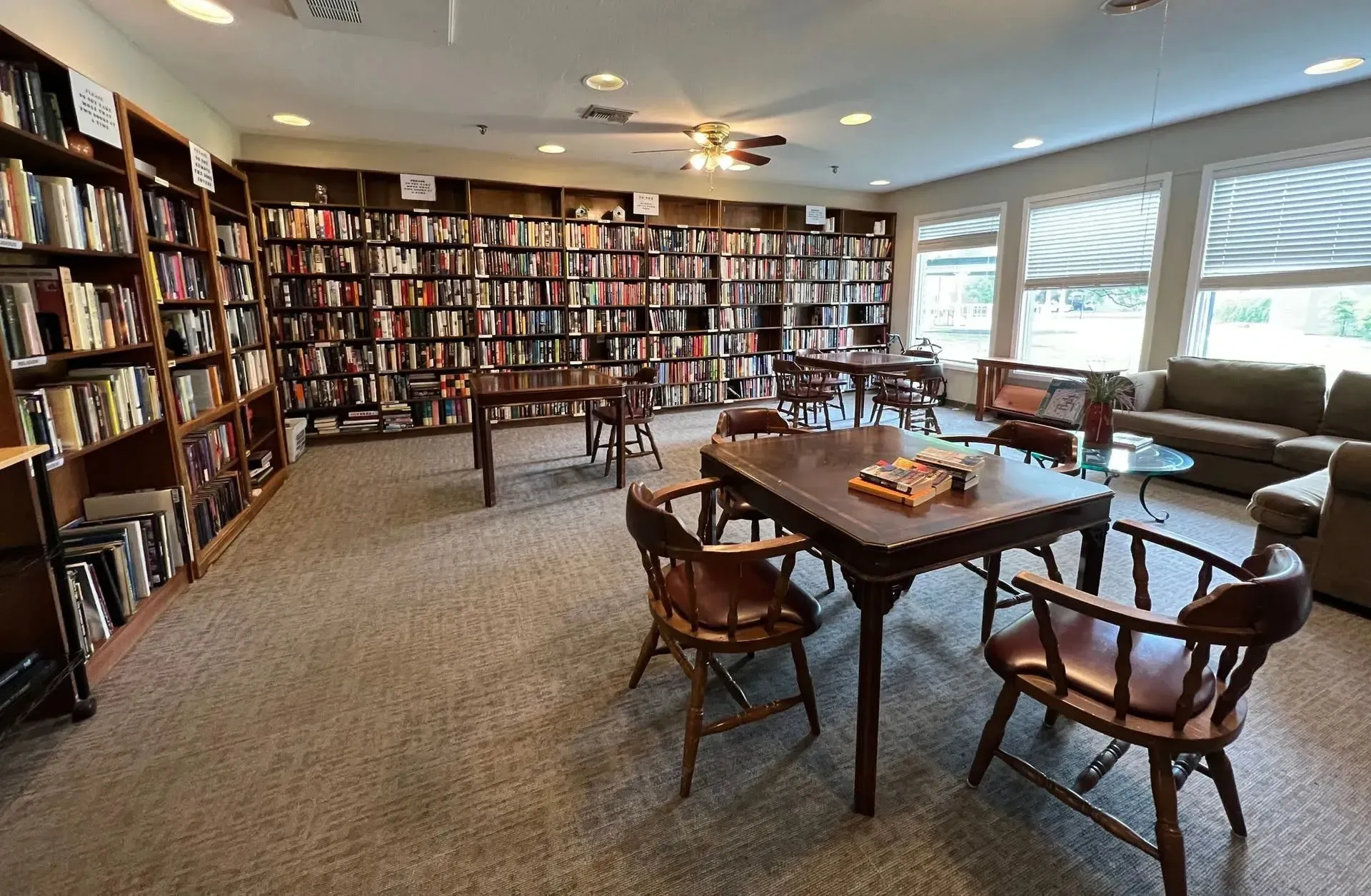 Tables and chairs arranged in a reading area at Treemont Senior Community in Houston, Texas