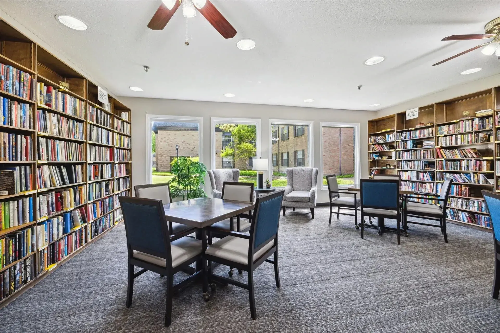 Bookshelves filled with books and seating area at Treemont Senior Community in Houston, Texas