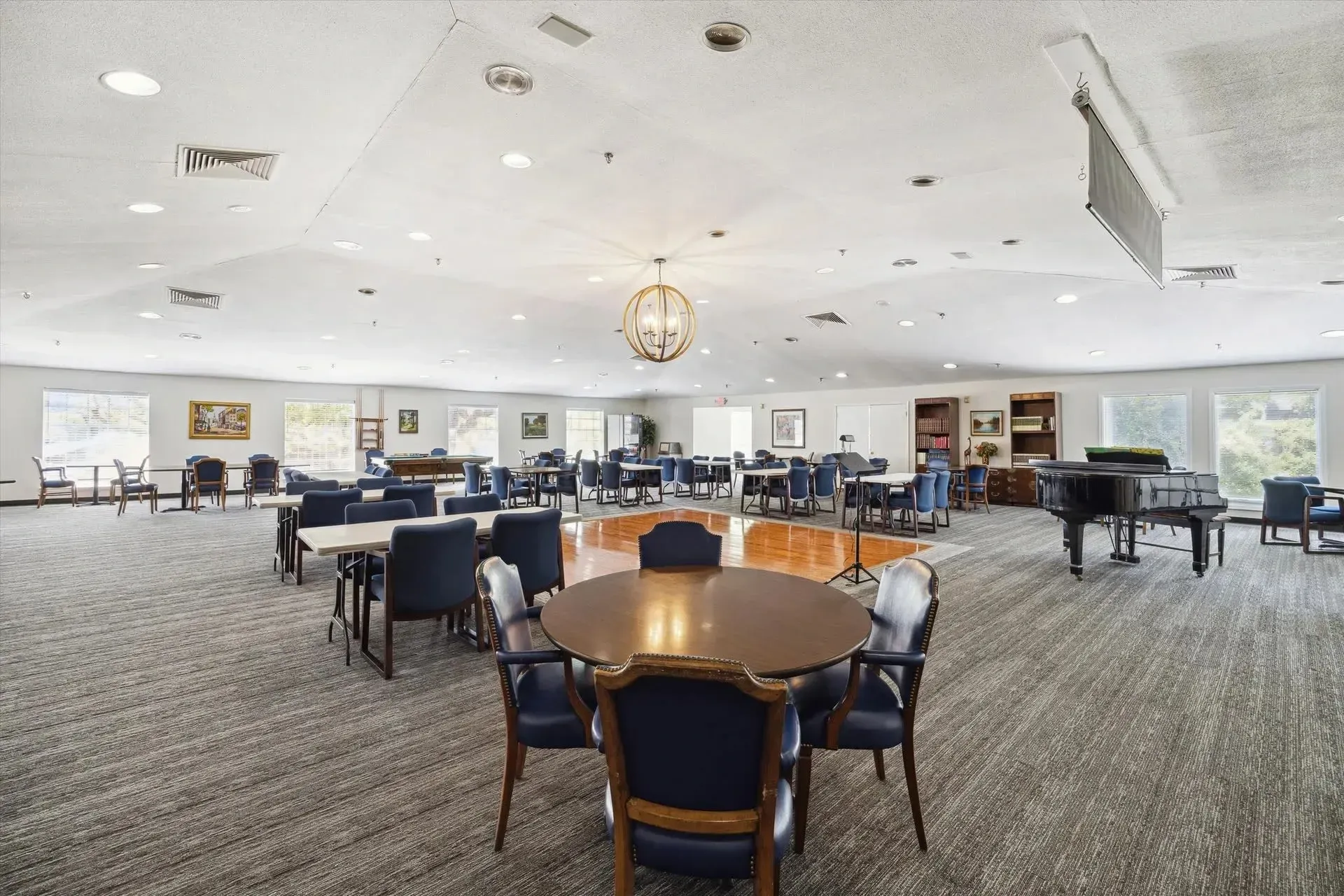 Piano with seating area and tables at Treemont Senior Community in Houston, Texas