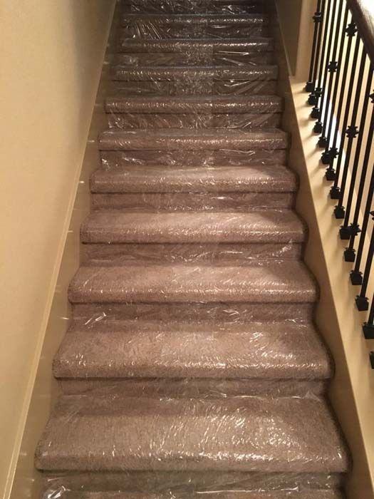 Staircase covered in plastic wrap, likely for protection during a move or construction.