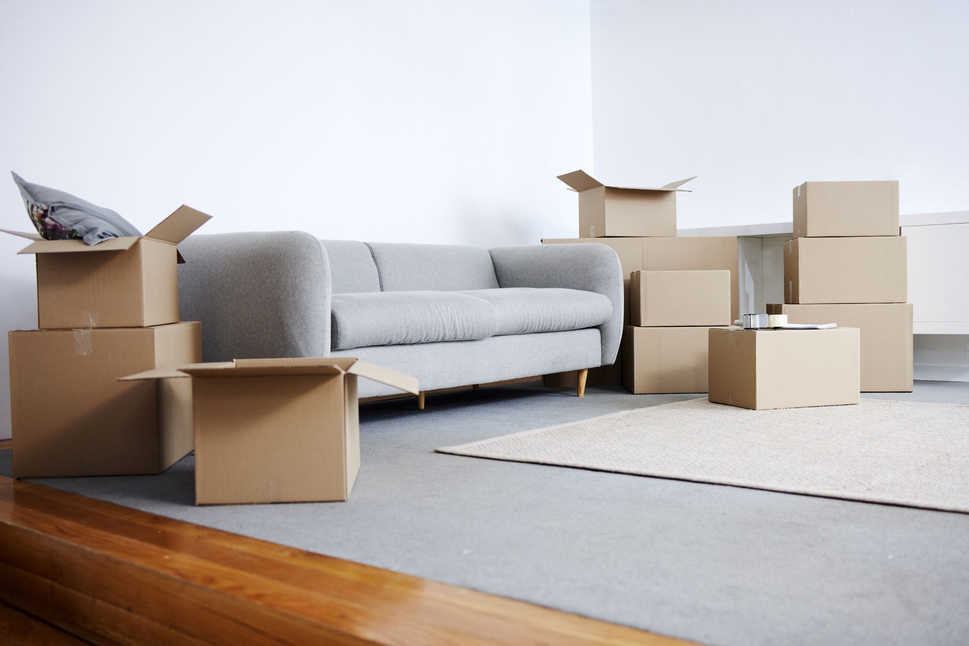 Boxes and a gray couch in a room, indicating a move.