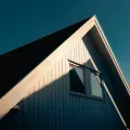 White house gable with a window, lit by warm sunlight against a dark blue sky