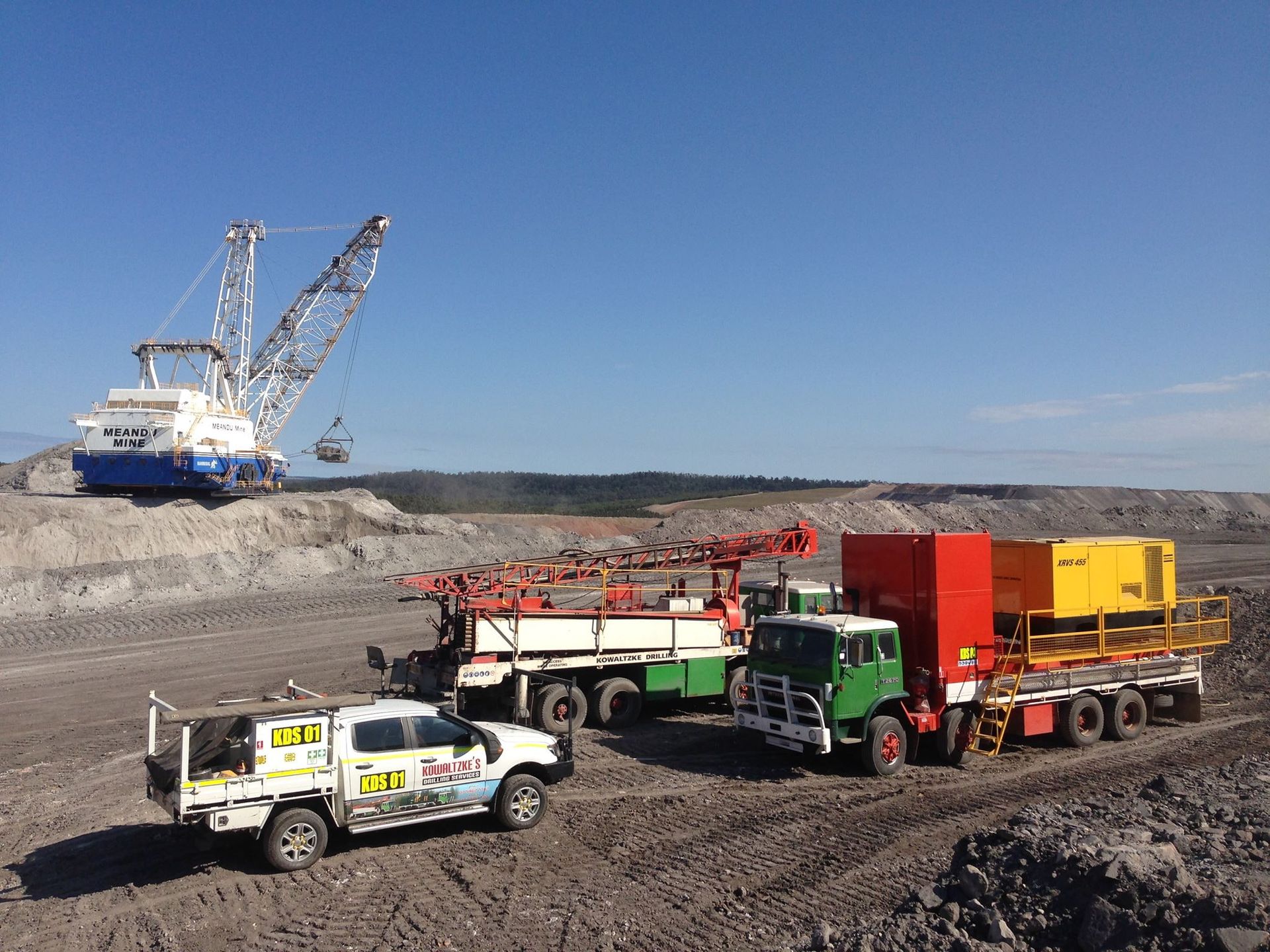 Trucks On a Mine Site With Large Bucket Excavator In Background — Kowaltzke Drilling Services in Highfields, QLD