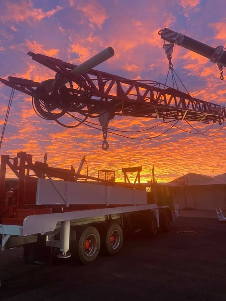 A Crane is Being Lifted by a Truck at Sunset — Kowaltzke Drilling Services in Gatton, QLD