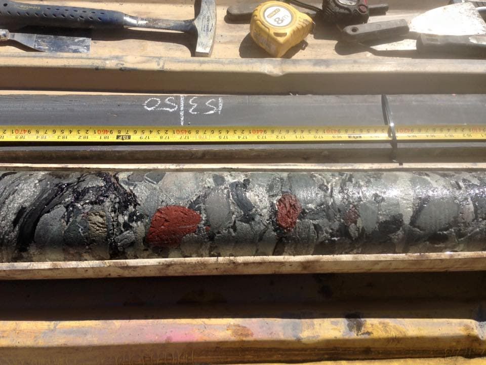 A Drill Bit is Sitting on a Wooden Table Next to a Tape Measure — Kowaltzke Drilling Services in Gatton, QLD