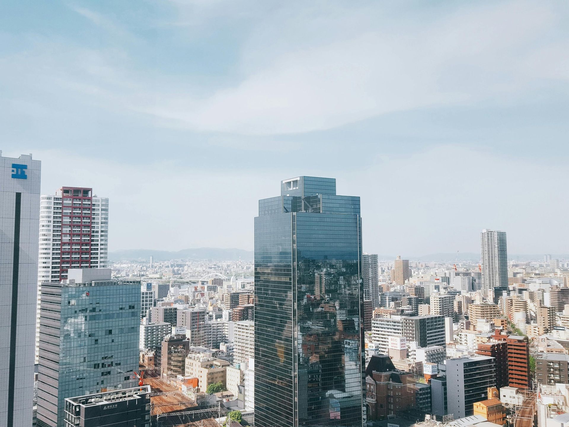 City skyline with tall glass office towers under a cloudy sky.