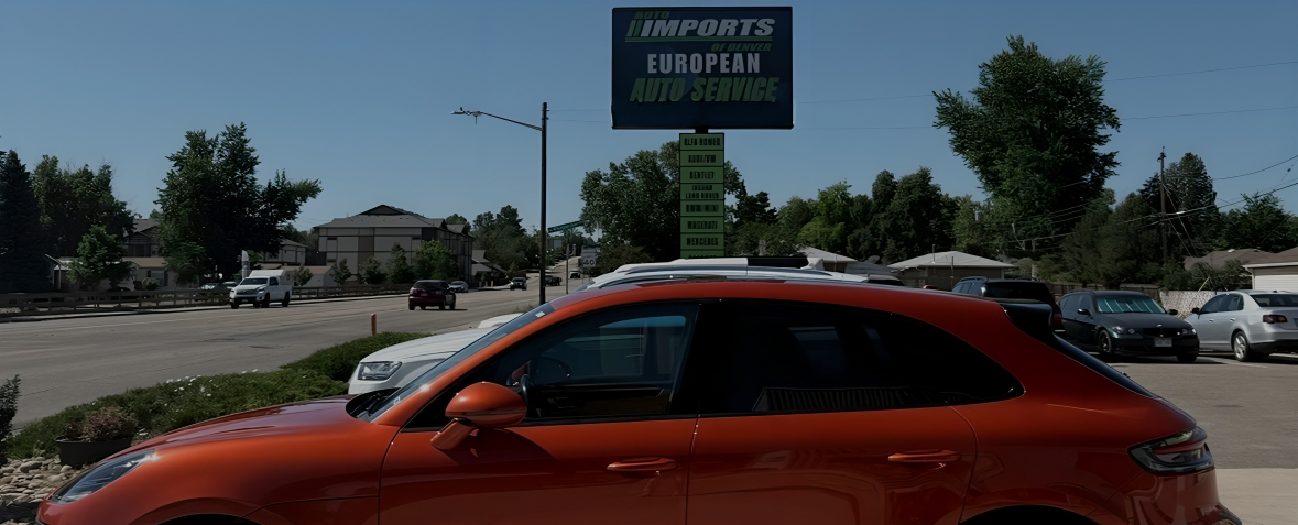 Orange car parked outside a storage facility under a roadside sign.  | AutoImports of Denver