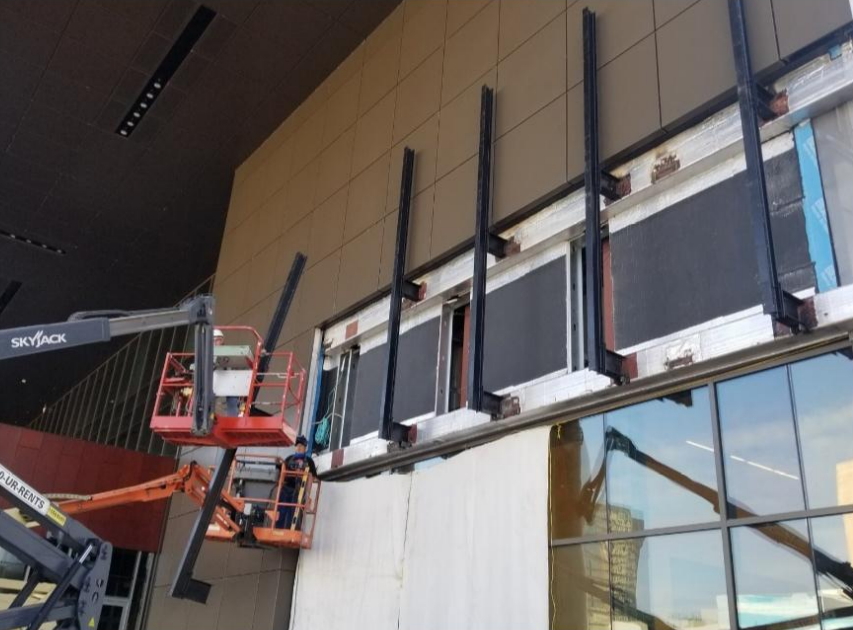A crane is being used to install a sign on the side of a building.