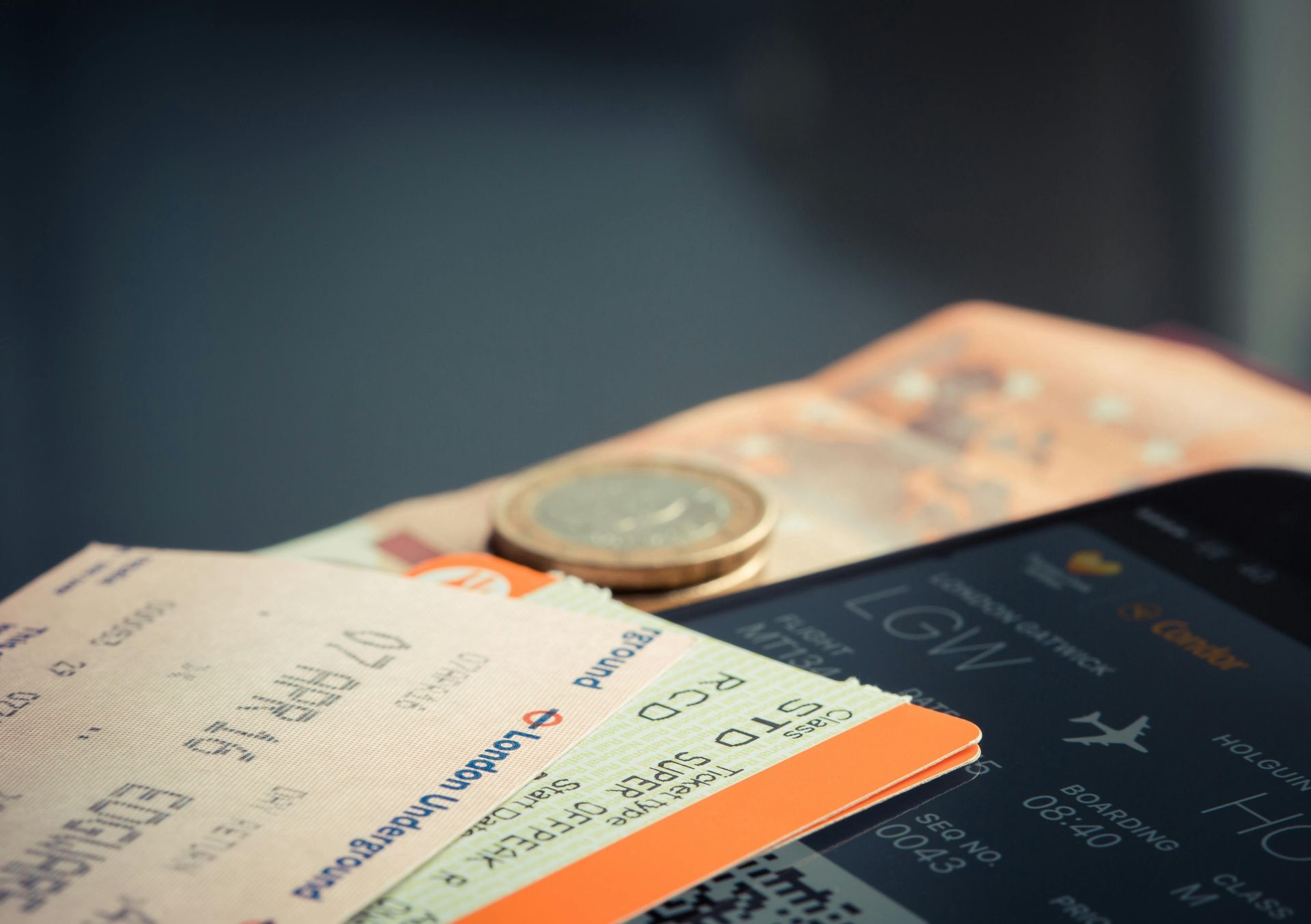 Passagens aéreas e moedas estrangeiras na tela de um smartphone, sugerindo planos de viagem.