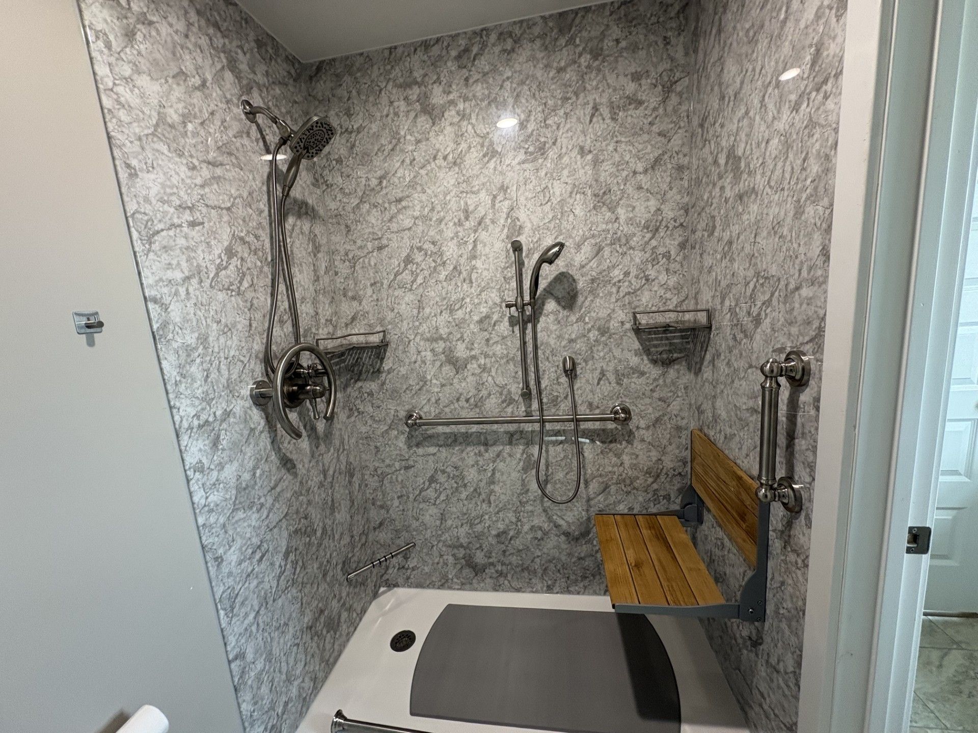 Accessible bathroom with sink, toilet, grab bars, and blue floral wallpaper