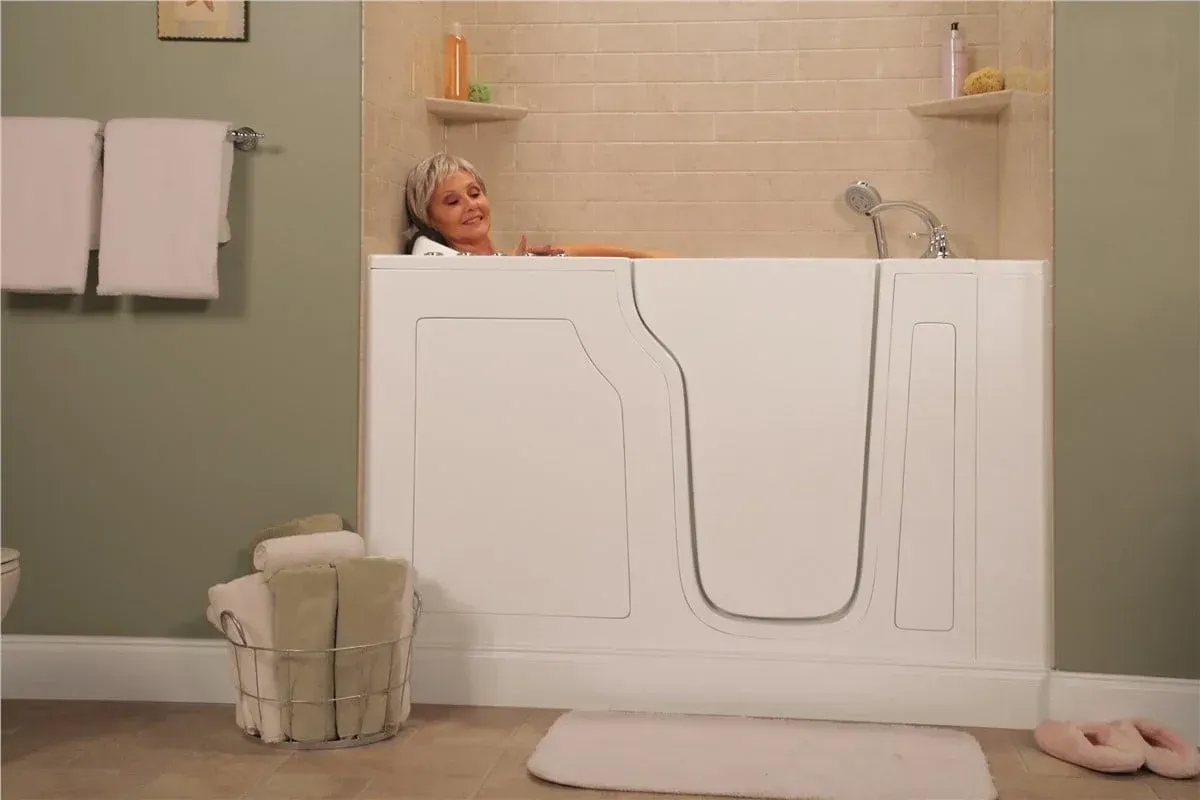 Empty white bathtub with chrome faucets against beige tiled bathroom walls