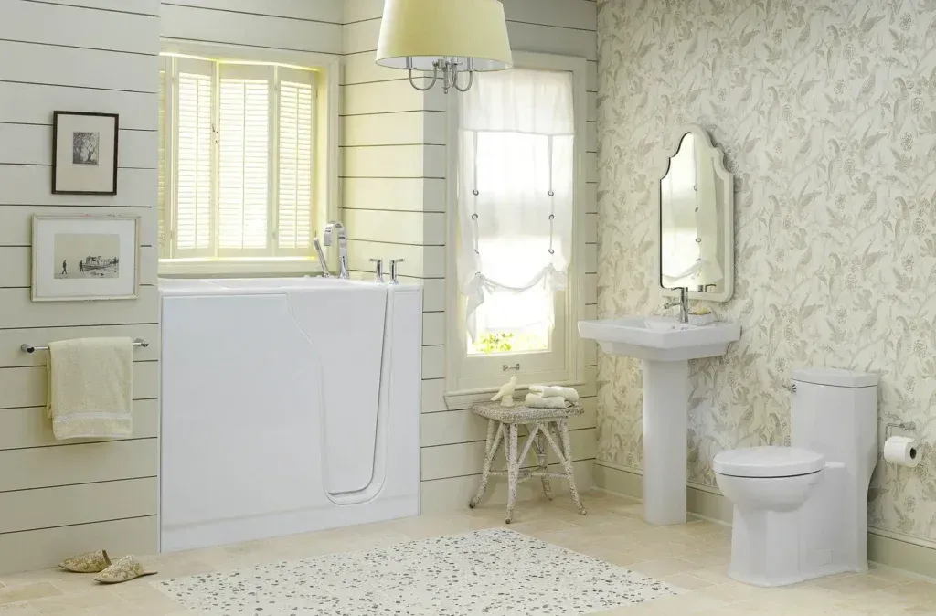 A bright, neutral-toned bathroom featuring a white walk-in tub, a pedestal sink, a toilet, and patterned wallpaper.