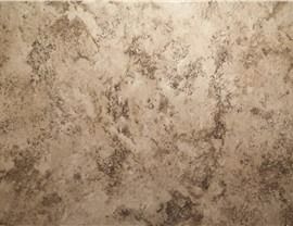 A close-up of a textured surface with mottled, earthy tones in shades of beige, tan, and dark brown.