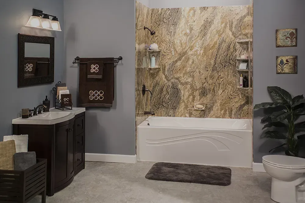 A modern bathroom with dark wood vanity, stone-patterned bathtub surround, gray walls, and a white toilet.