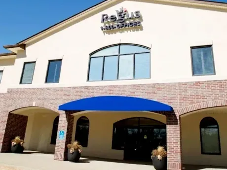 Exterior of a beige building with a blue awning and arched entrance
