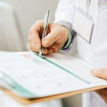 Close-up of a doctor writing on a clipboard in a white coat