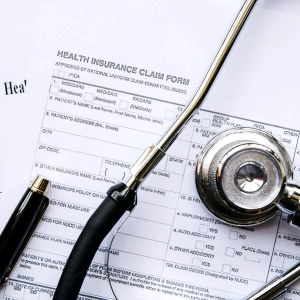 Health insurance claim form with stethoscope and pen on white background