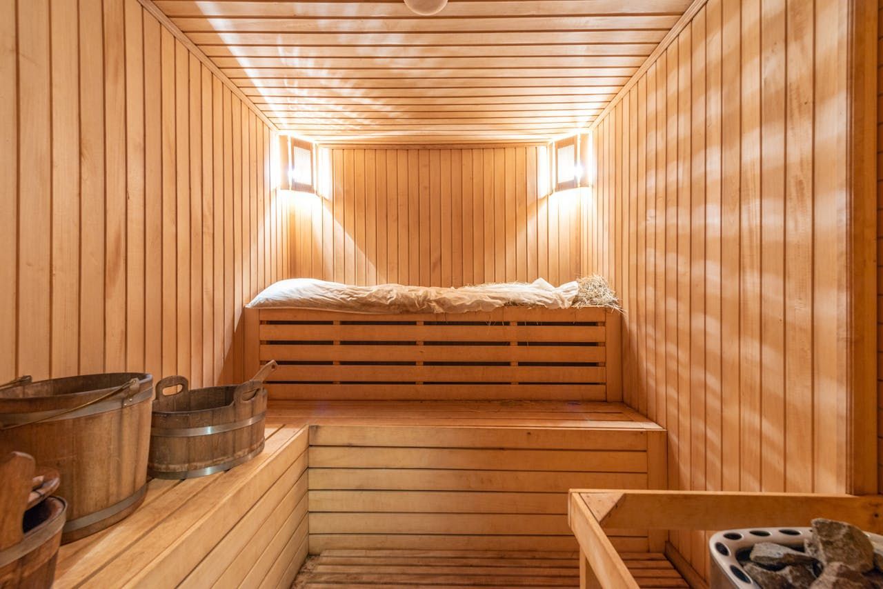 A Wooden Sauna With Benches, Wooden Buckets, and a Heater With Hot Stones — Intouch Pools & Spas in Forster, NSW
