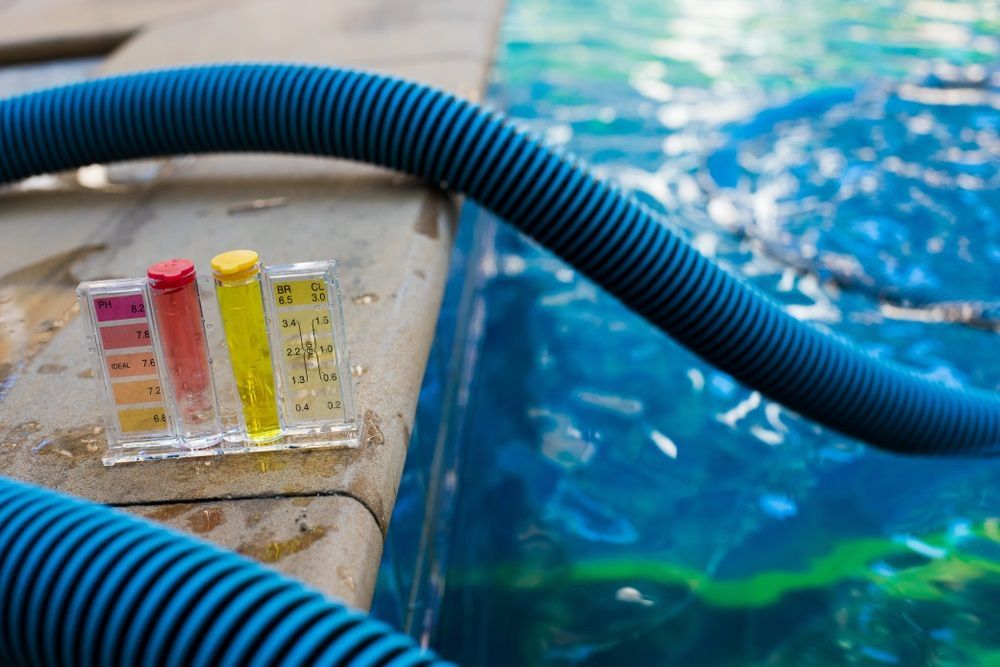 Pool Water Test Kit With Color Indicators on a Pool's Edge, Next to a Blue Hose; Measuring Water Quality — Intouch Pools & Spas in Forster, NSW
