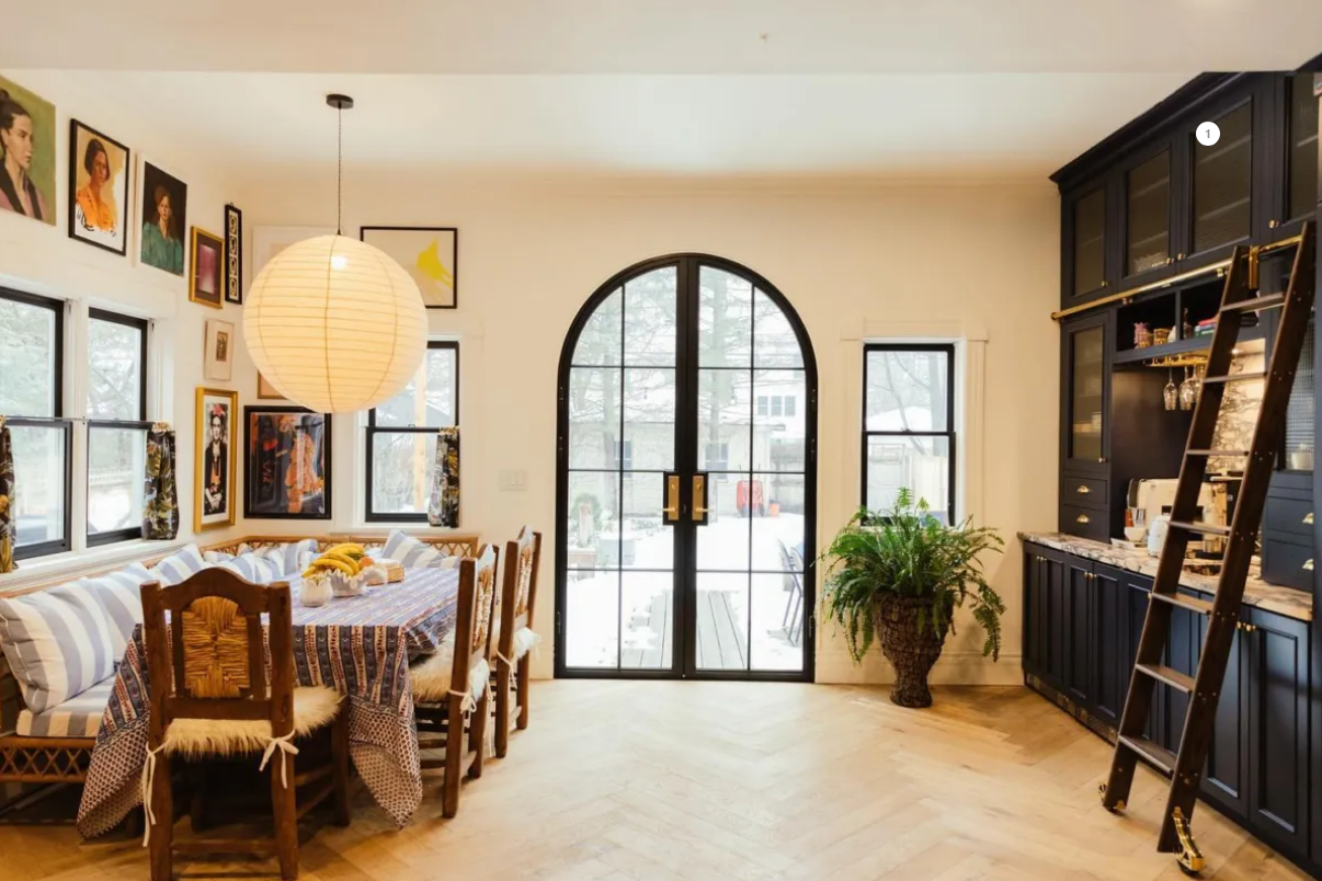 Dining room with a large archway, art-lined walls, and a dark cabinet with a ladder.