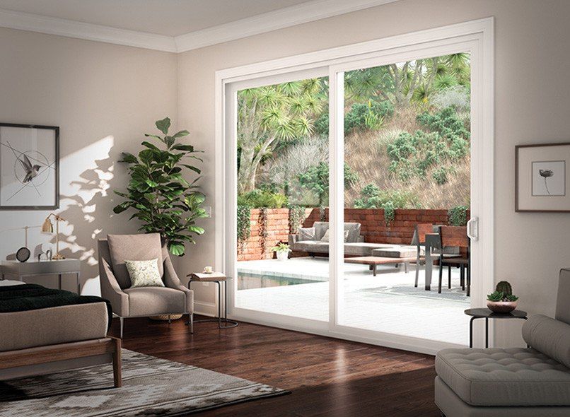 Living room with sliding glass door, outdoor patio, and lush greenery.
