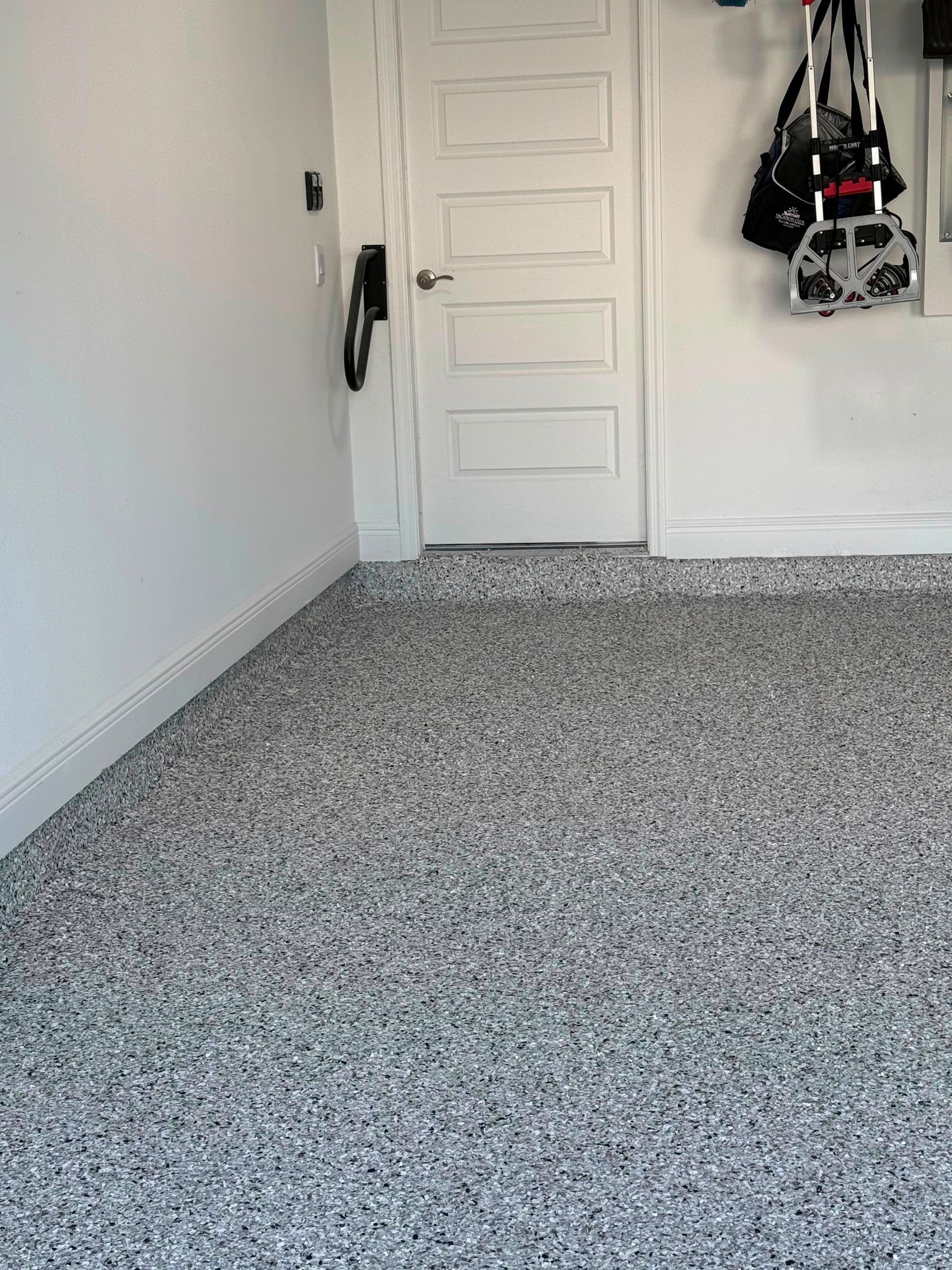 Empty carpeted room with white walls, a white door, and hanging items on the wall