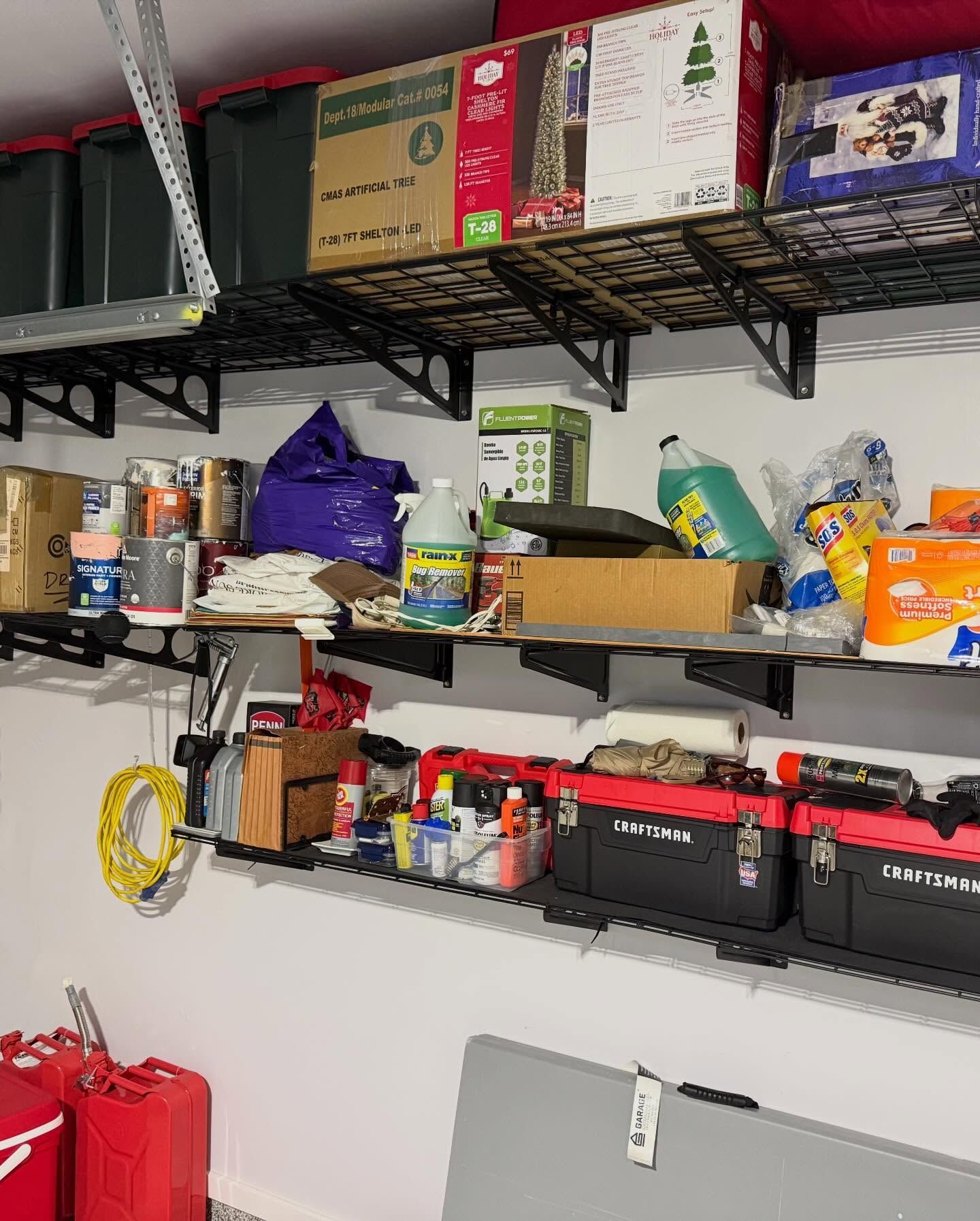 Shelving in a garage storage area with boxes, tools, and assorted supplies along the wall