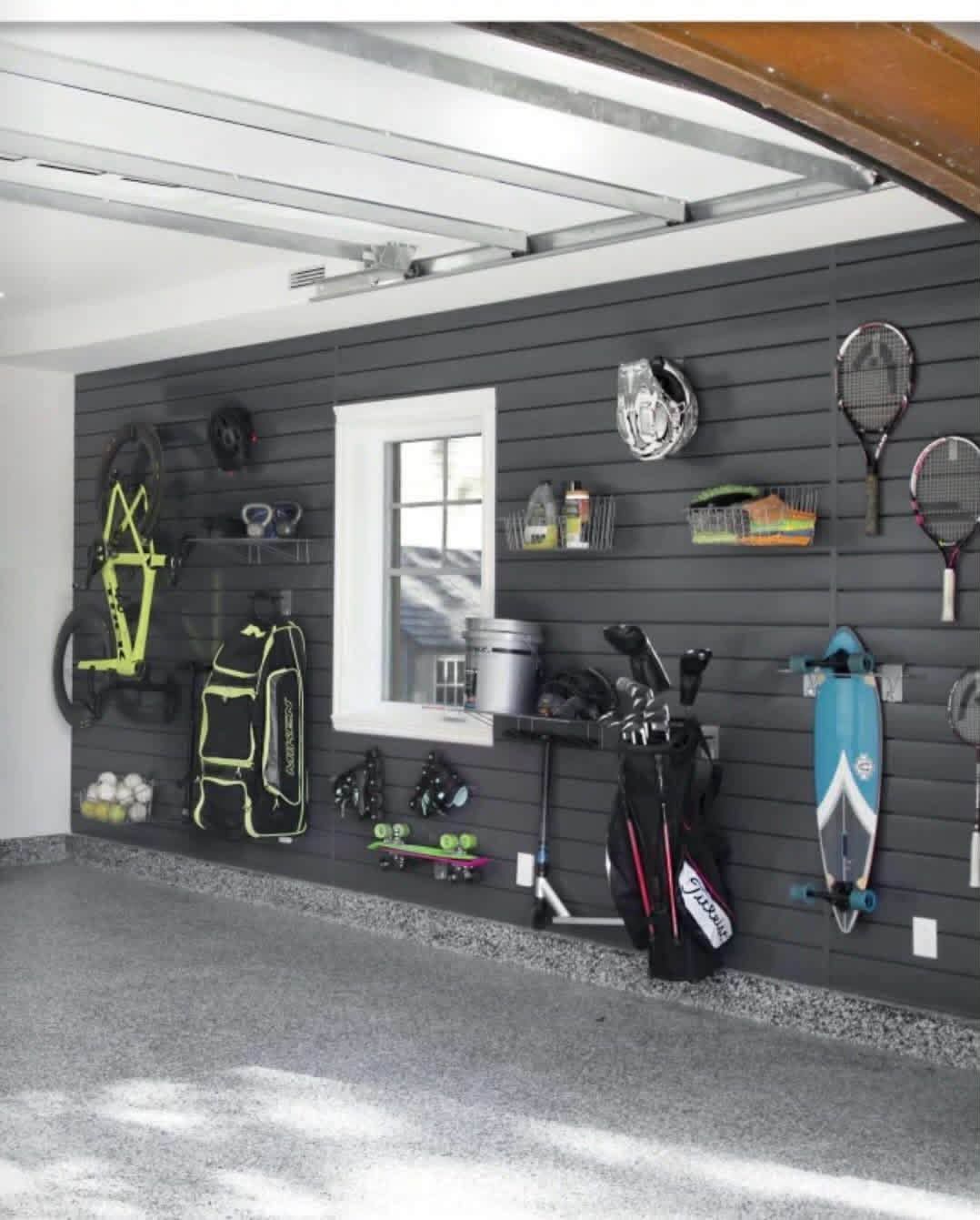 Garage with sports gear and tools neatly organized on dark slatwall panels.