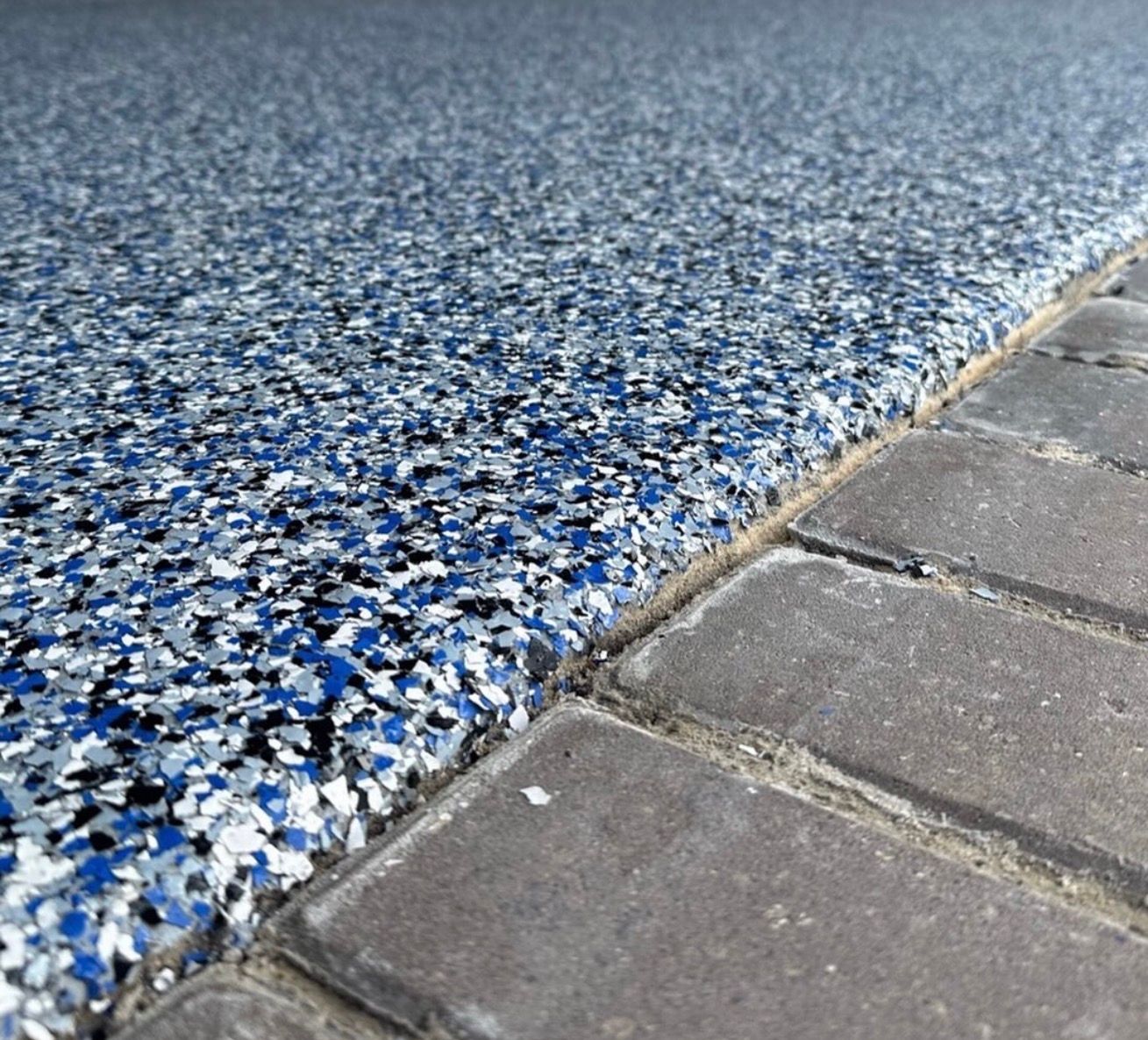 Blue and white speckled textured surface beside gray paving stones