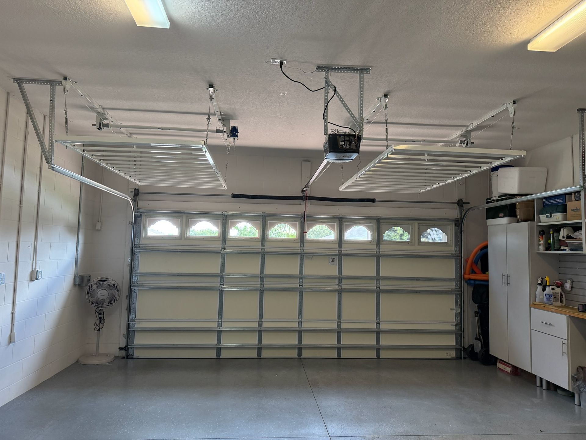 Empty two-car garage with open door, overhead tracks, and a workbench along the right wall.