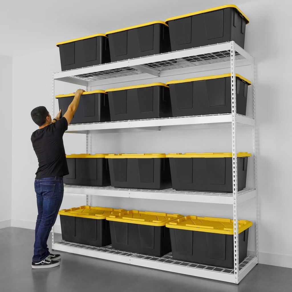 Person reaching toward black storage bins on a white shelving unit in a warehouse-like room