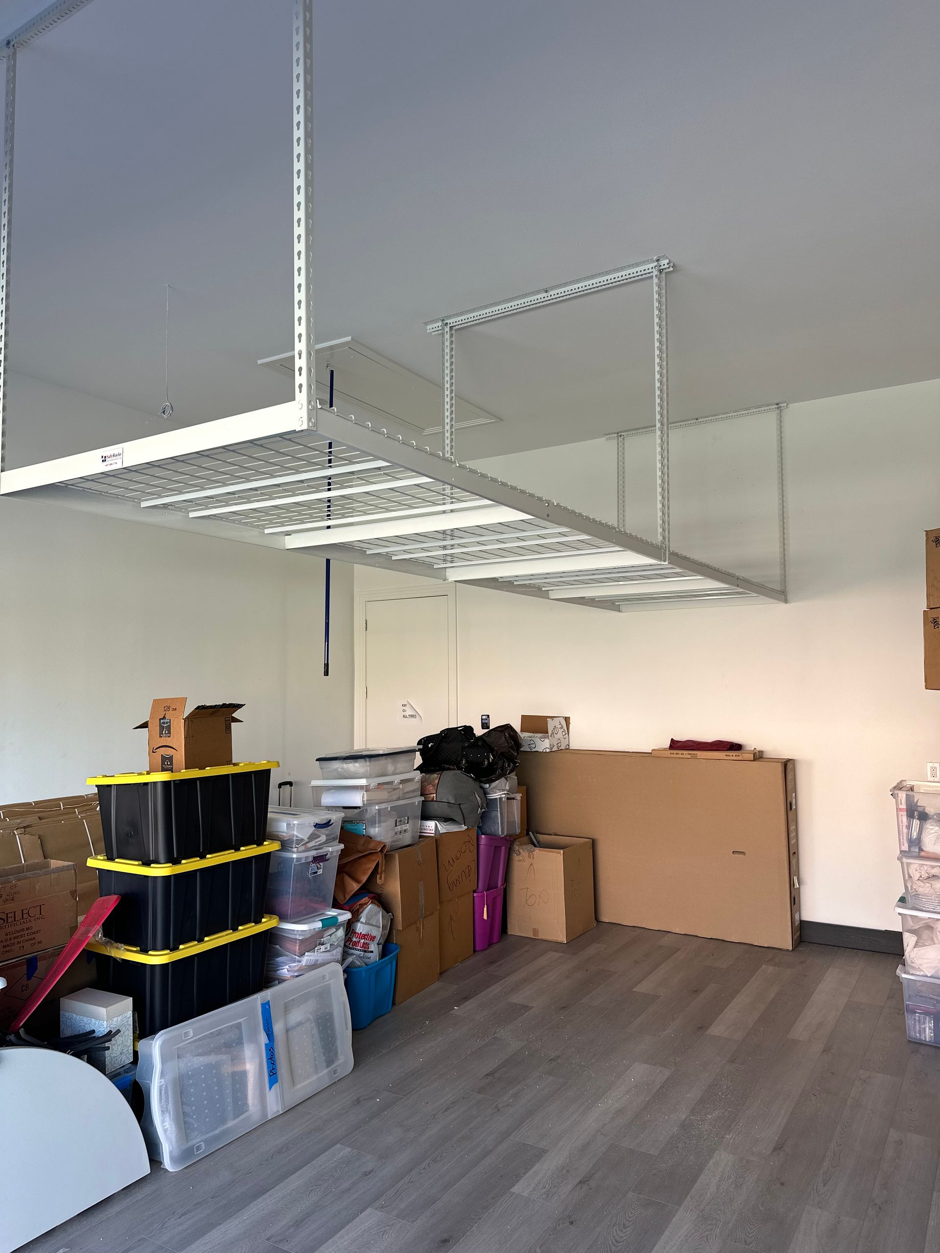 Storage room with shelving, stacked boxes, and a hanging metal rack near the ceiling