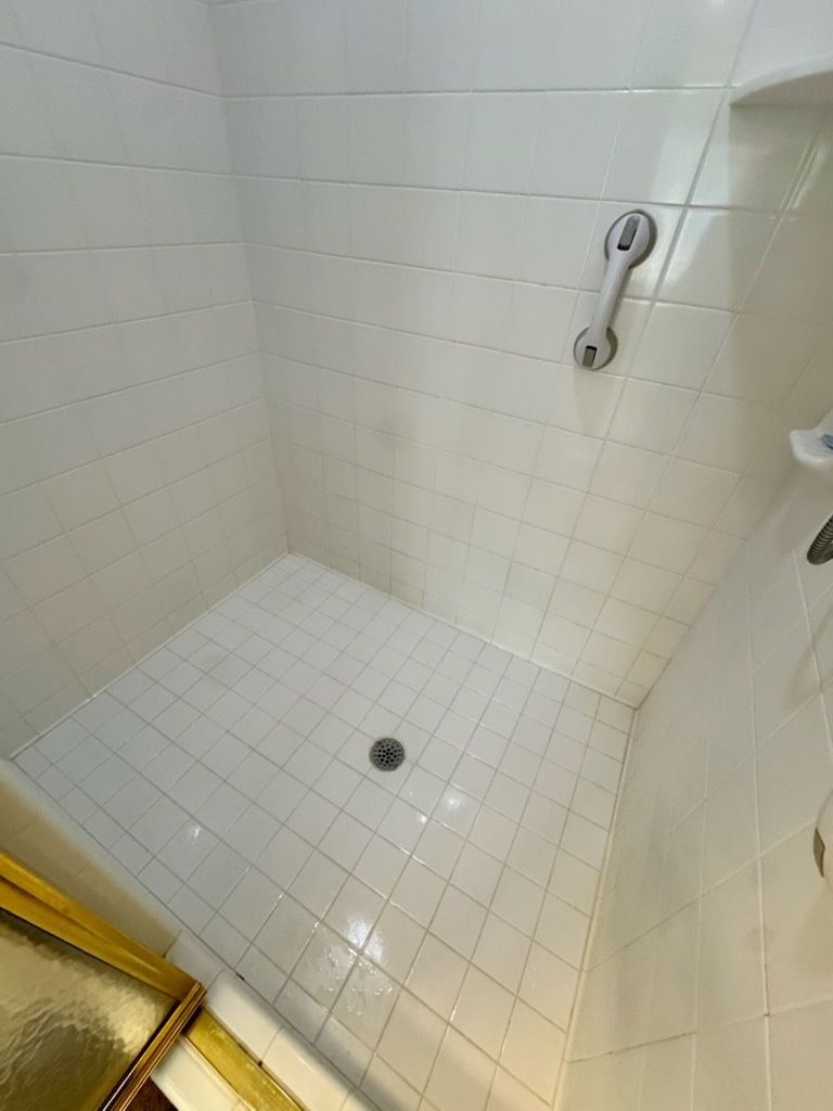 Gloved hands cleaning a white bathroom sink with a spray bottle and blue cloth