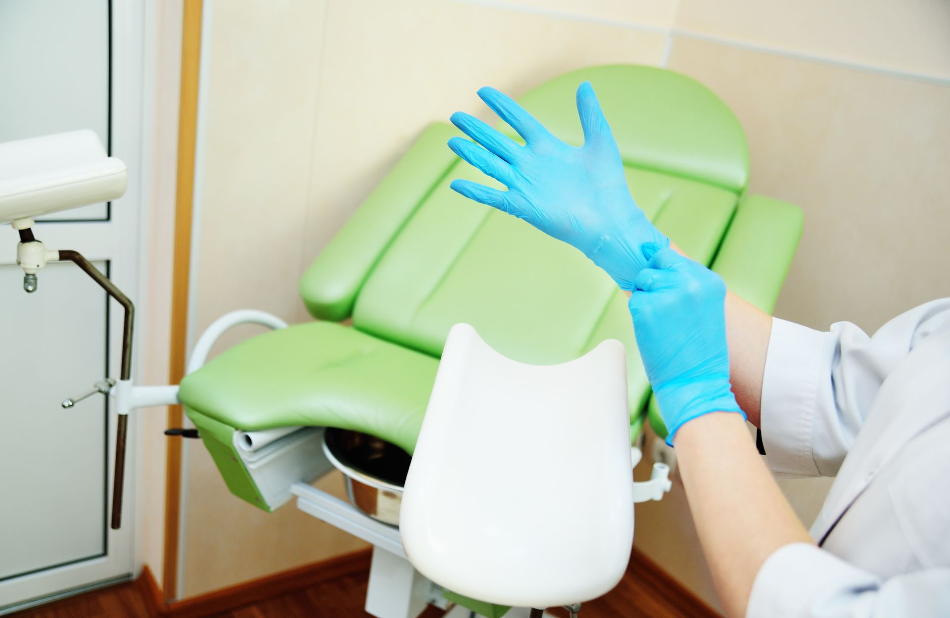 doctor gynecologist putting on rubber gloves prepares for examination against.