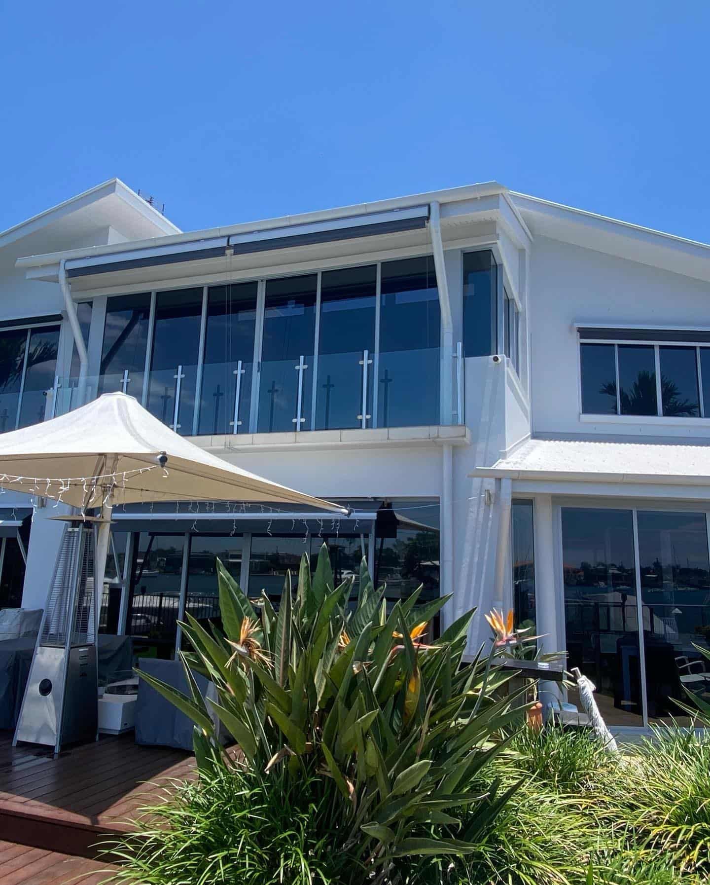 A Large White House With A Lot Of Windows And Umbrella — Home Tint Sunshine Coast Window Tinting In Maroochydore, QLD