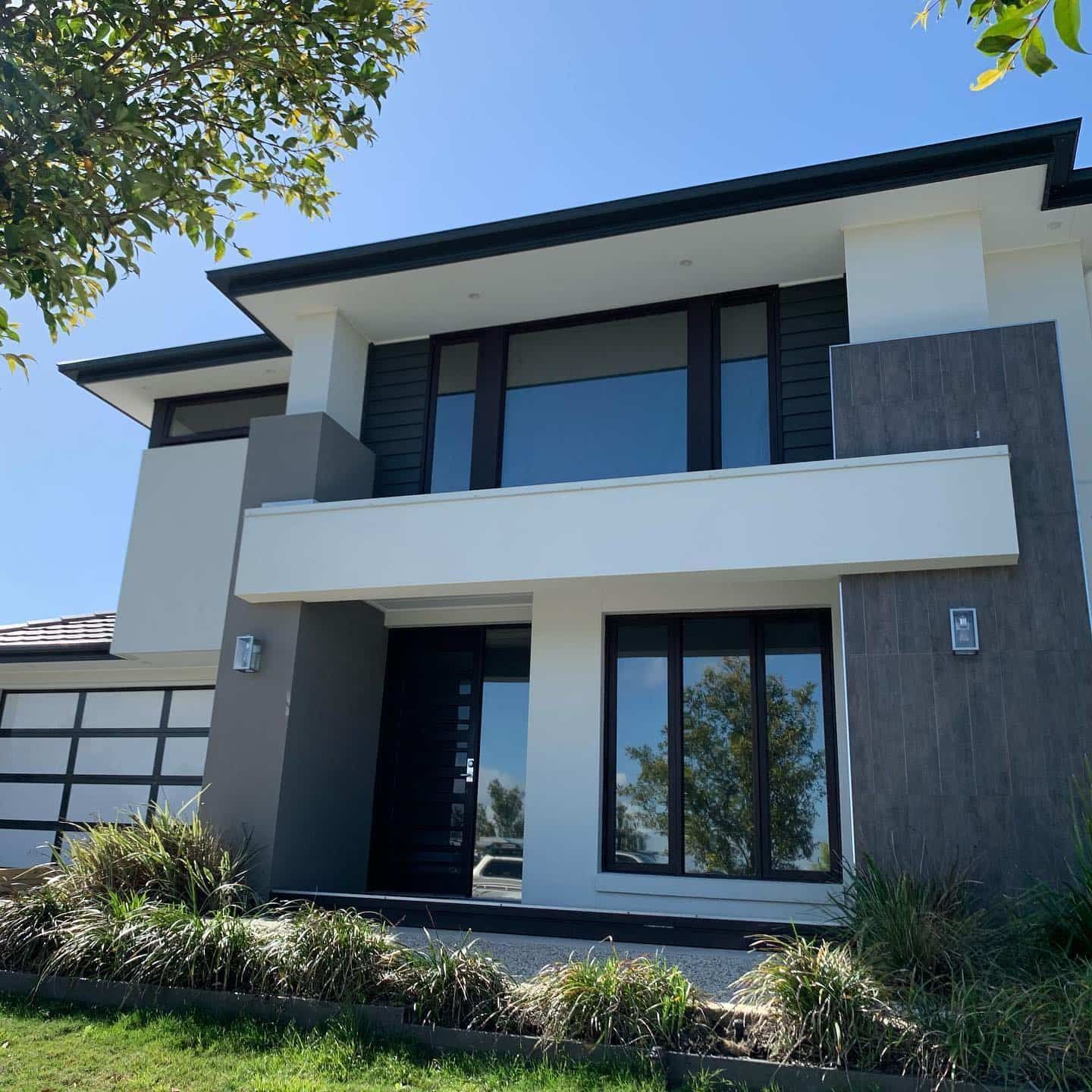 A Large White House With Black Windows And A Garage Door — Home Tint Sunshine Coast Window Tinting In Noosa, QLD