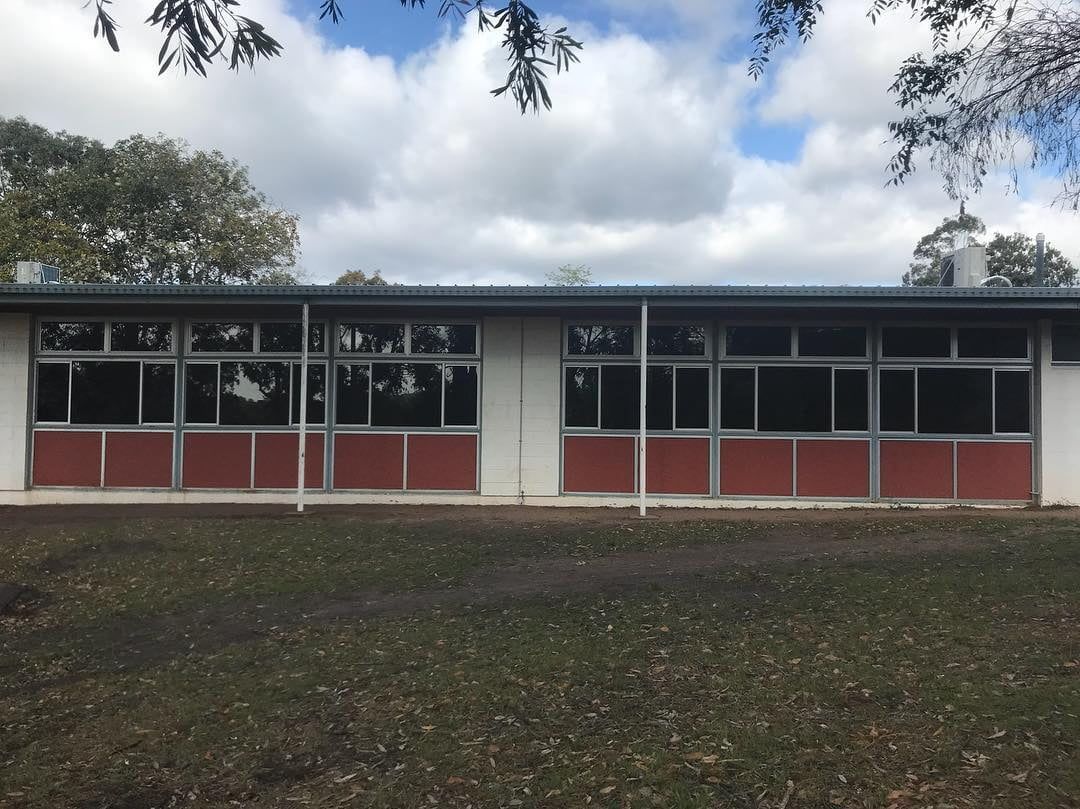 A Large Building With A Lot Of Windows Is Sitting In The Middle Of A Grassy Field — Home Tint Sunshine Coast Window Tinting In Maroochydore, QLD