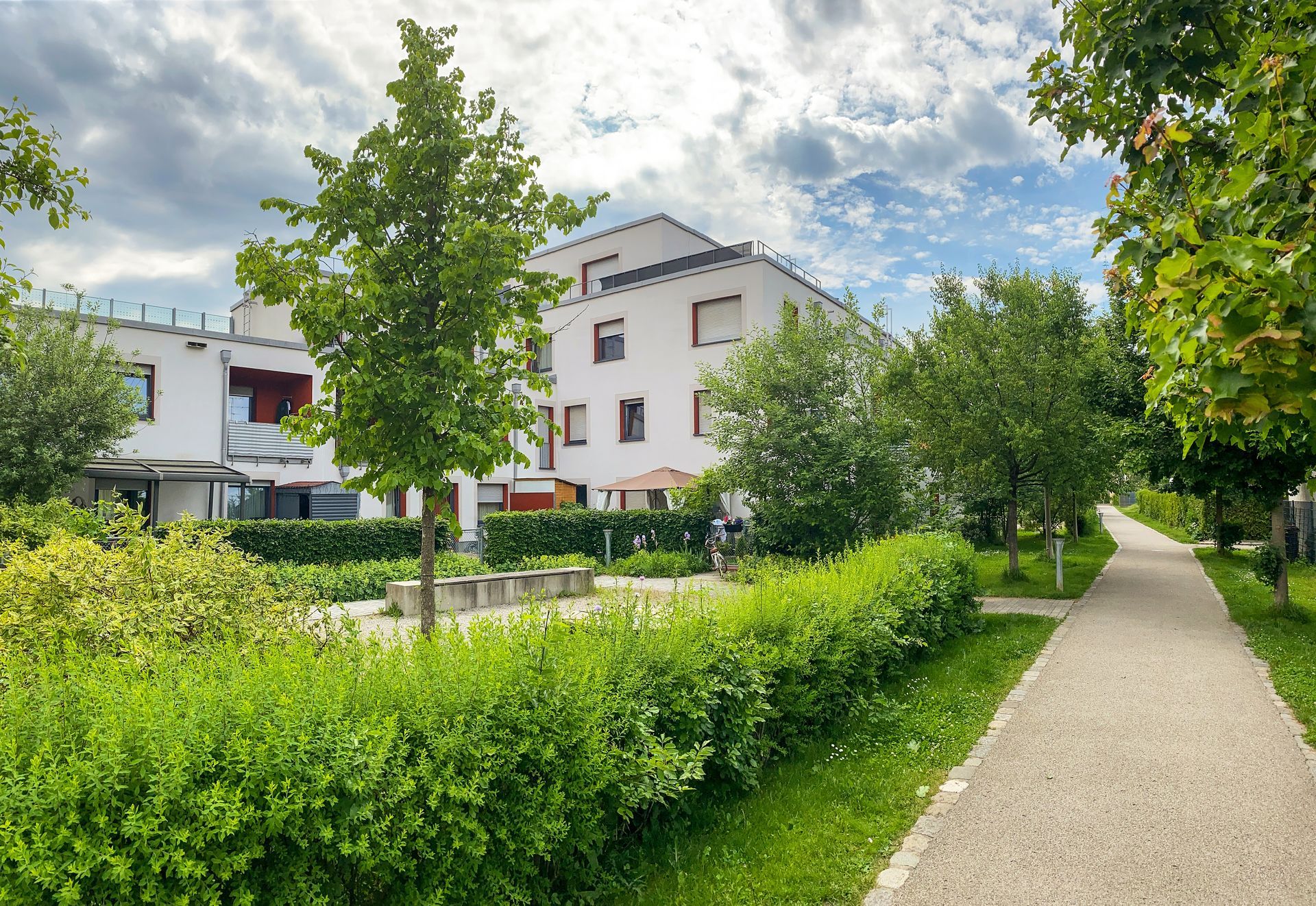 Ein weißes Gebäude ist von Bäumen und Büschen in einem Park umgeben.