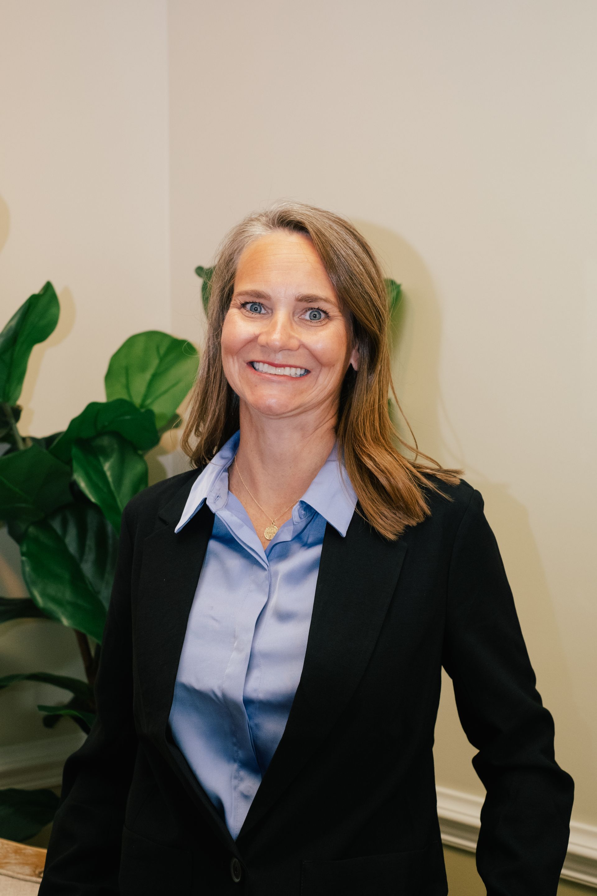 A woman in a suit and blue shirt is smiling for the camera.