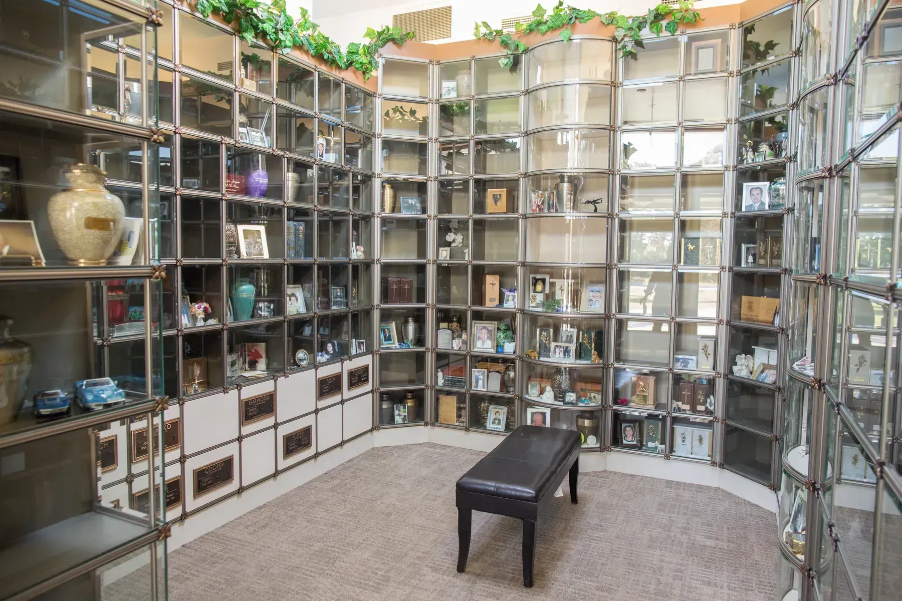 Small tiled courtyard with wall-mounted shelves of objects and a black bench in the center.