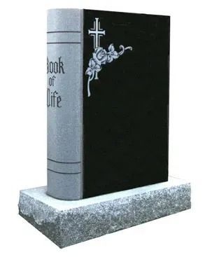 Black memorial book-shaped gravestone with a cross and flowers on a gray base